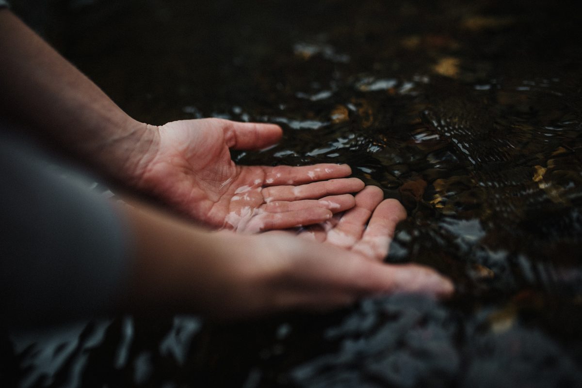 Cupped hands touching the surface of a clear mountain stream