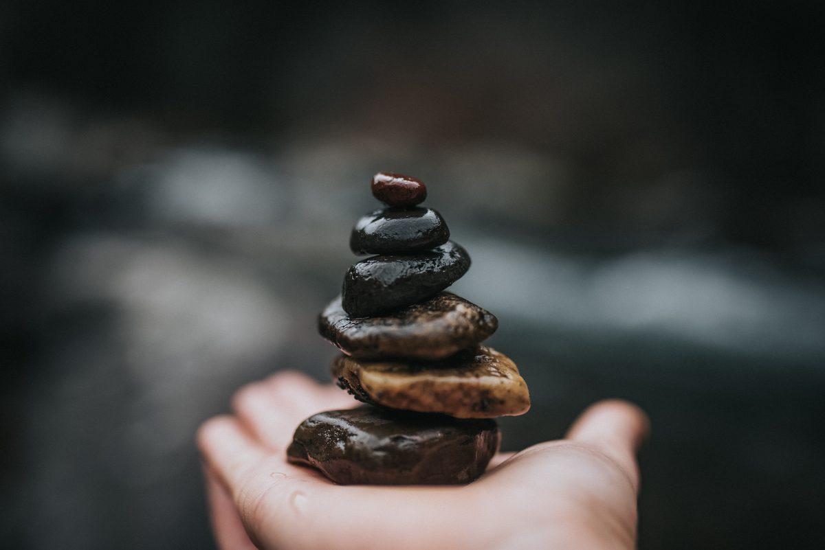 A small cairn of balanced river stones resting in an open palm